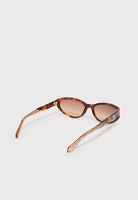 Okulary przeciwsłoneczne w kolorze muszli żółwia o owalnym kształcie, z brązowymi soczewkami z efektem gradientu oraz wypolerowanymi zausznikami z subtelnym logo.