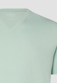 T-shirt vert clair à manches courtes avec col en V, logo s.Oliver discret sur la poitrine et étiquette intérieure du col indiquant la taille 2XL.