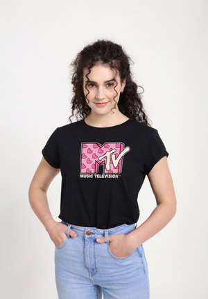 Černé tričko s krátkým rukávem s růžovým logem MTV a vzorem srdcí, spárované se světle modrými vysokými džíny.