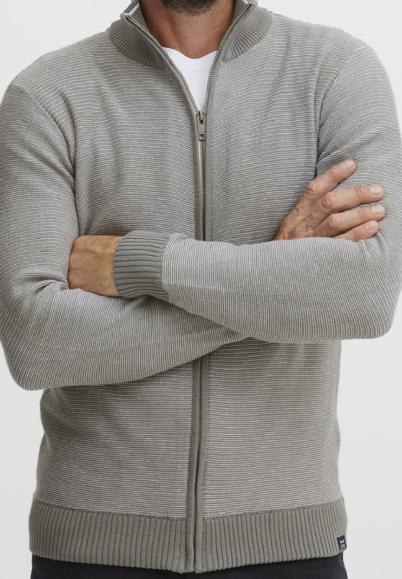 Grauer Reißverschluss-Pullover mit geripptem Kragen und Bündchen. Mit horizontalen Streifen und slim-fit Design. Strukturierter Strickstoff.