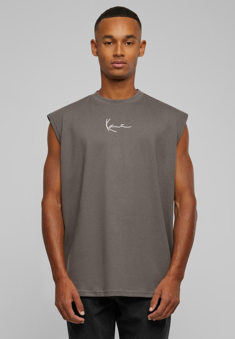 Grå ärmlös t-shirt med rund halsringning, tillverkad av mjukt material, med en vit signaturlogotyp på bröstet. Enkelt design, avslappnad passform.