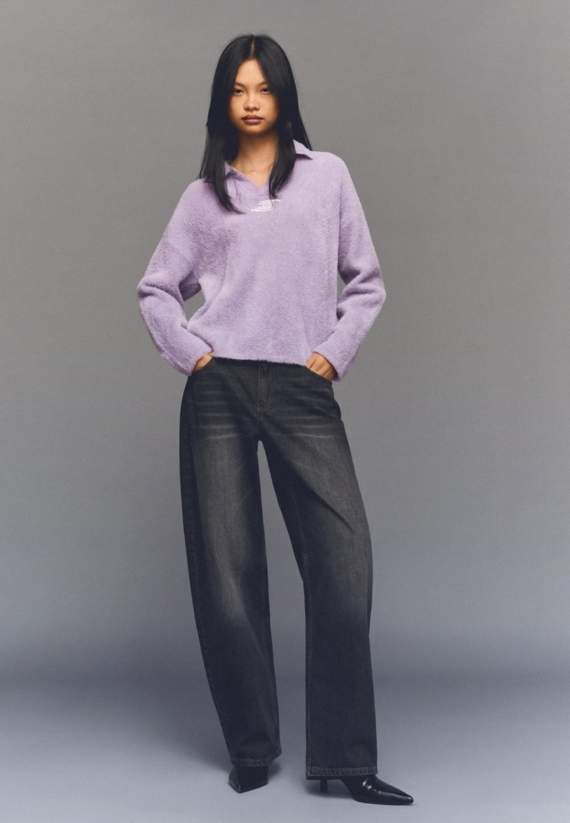 Lavenderfarbener Plüsch-Pullover mit Kragen, kombiniert mit dunklen, hochgeschnittenen, weit geschnittenen Jeans und schwarzen spitzen Schuhen. Glatte Textur und lockere Passform.