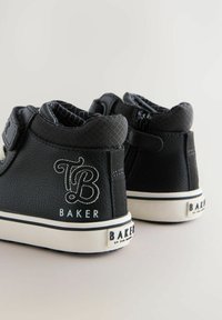 Mustaläikivad kõrge šnööriga tossud tekstuuriga aktsentidega, valged kummist tallad ja detailne õmblus. Küljel on logo "TB BAKER".