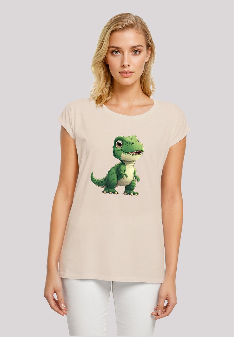 Beige cotton t-shirt with a short sleeve design featuring a green cartoon dinosaur printed on the front.