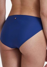 Bas de maillot de bain bleu avec une texture lisse, comportant un petit accent métallique à l'arrière. Conçu pour le confort avec une forme de couverture modeste.