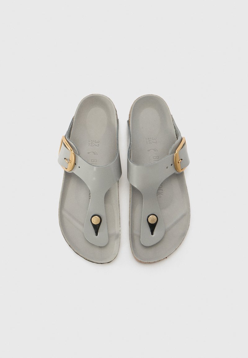 Szare kauczukowe sandały z paskiem w kształcie litery V, złotym akcentem w postaci klamry oraz czarnymi okrągłymi detalami na pasku palca. Płaskie podeszwy o fakturowanej powierzchni.