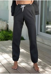 Donkergrijze joggingbroek met elastische boorden en een trekkoord in de taille. Voorzien van zijzakken en een gladde, zachte textuur.