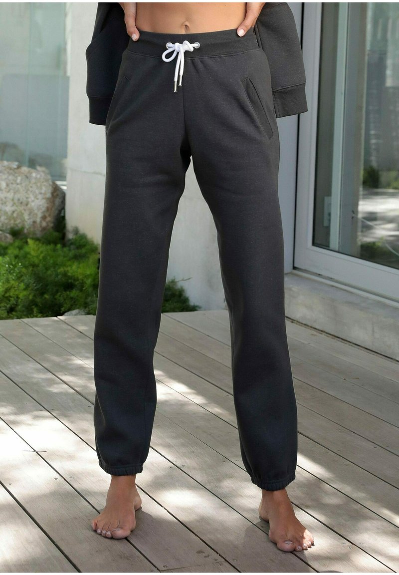 Donkergrijze joggingbroek met elastische boorden en een trekkoord in de taille. Voorzien van zijzakken en een gladde, zachte textuur.