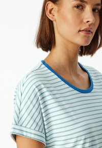 T-shirt a strisce blu chiaro realizzato in tessuto morbido, con scollatura rotonda bordata di un blu in contrasto e maniche corte arrotolate.