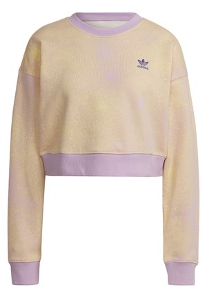 Sudadera corta de color beige claro con cuello, puños y dobladillo acanalados en color lavanda, y pequeño logo púrpura de Adidas en el pecho izquierdo.
