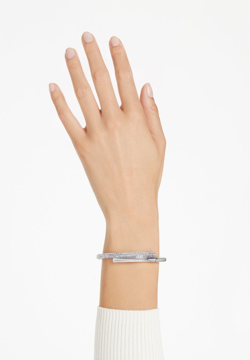 Bracciale d'argento con una fascia testurizzata adornata da piccole pietre e un elegante accento metallico lucido. Indossato su una mano.