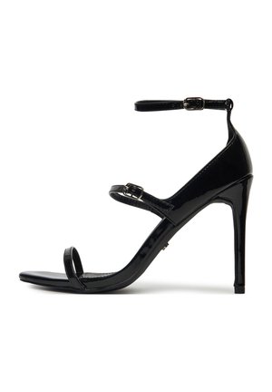 Sandalo con tacco alto in pelle verniciata nera, caratterizzato da tre sottili cinturini e fibbie d'argento alle caviglie e al centro del piede.
