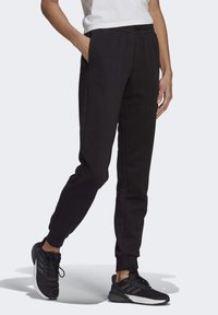 Svarta atletiska joggers med elastiskt midjeband, sidofickor och åtsittande mudd. Matchat med svarta löparskor med strukturerad design.