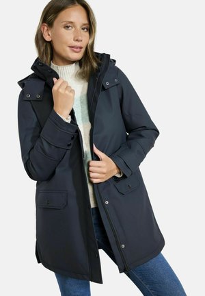 Veste imperméable bleu marine foncé avec capuche, fermeture éclair à l'avant, boutons-pression et deux poches avant. Texture douce et lisse, design décontracté.