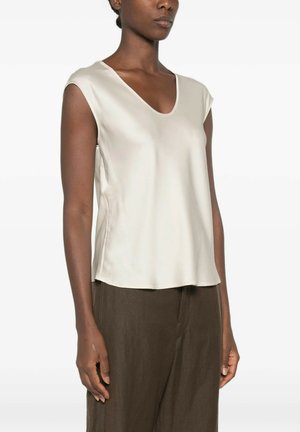 Donna che indossa una camicetta senza maniche in raso crema con scollo a barca e pantaloni larghi marrone scuro su sfondo bianco.