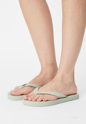 Minzgrüne Flip-Flops mit einem Riemendesign, strukturiertem Sohle und einer flachen, breiten Fußbett. Aus Gummi, im Slip-On-Stil.