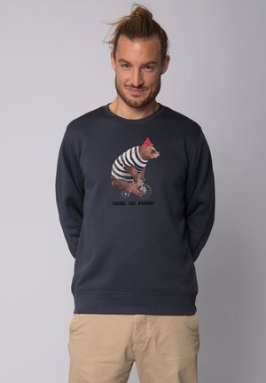 Marineblauwe crewneck sweatshirt met een beer in een gestreept shirt en een rode beanie, bedrukt op de voorkant. Casual ontwerp, zachte textuur.