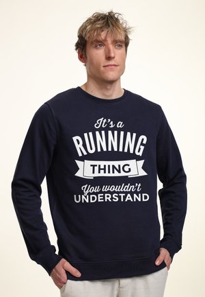 Felpa navy in cotone, con testo bianco in tipografia bold: "È una COSA di CORSA. Non potresti COMPRENDERLA". Design classico con collo a giro.