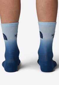 Blå gradient ankelsockor i ribbat material, med en mörkblå tå och häl, samt en logotyp tryckt i marinblått på sidan.