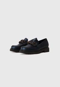 Navy leather loafers with a chunky black sole, featuring a decorative chain accent across the front and smooth texture.