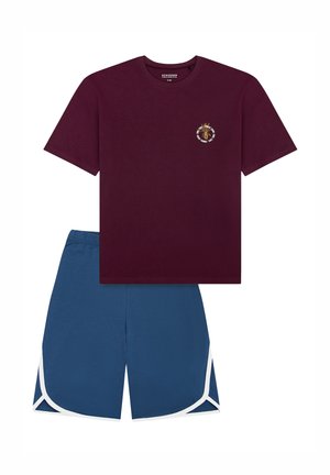 Maroon cotton t-shirt with a circular emblem, paired with blue athletic shorts featuring white side accents and an elastic waistband.