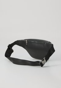 Banane en simili cuir noir avec une forme incurvée, fermeture zippée et sangle en nylon ajustable. Texture lisse avec des accents en métal argenté.