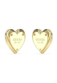 Herzförmige Ohrringe aus Gold mit der eingravierten Aufschrift "GUESS EST. 1981" auf jeder Seite, sichtbaren Hardware-Details und einer polierten Oberfläche.