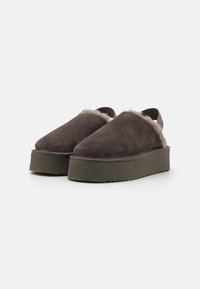 Brune suedeslip-on sko med en fluffy beige trim og en tykk grønn plattformsåle med en sikksakk-kant.