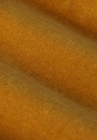 Tissu doux et texturé dans une riche couleur ambre doré, présentant une finition lisse avec de subtiles variations de teinte et de profondeur.