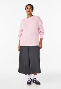 Svetloružový pletený sveter so vzormi srdiečok, široká sivá plisovaná sukňa, biele ponožky a modré tenisky s ružovými šnúrkami. Neformálny, pohodlný strih.