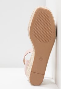 Sandale plateforme rose avec un talon en espadrille texturé, dotée d'un design de bride lisse et d'une semelle en caoutchouc avec des rainures pour une bonne adhérence. Taille 37.