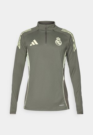 Dark green long-sleeve top with half-zip collar, light green stripes on shoulders, and embroidered club logo, made from lightweight fabric.