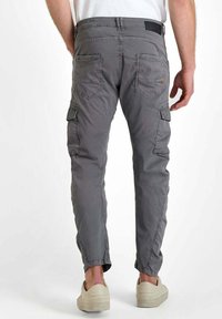 Grijze cargo broeken met een slim fit, voorzien van zijzakken, achterzakken, riemlussen en een lichte textuur. Gedragen met lichtgekleurde sneakers.