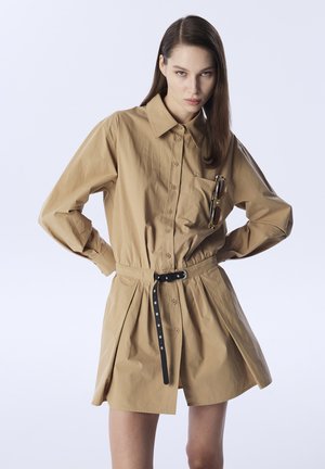 Beige Hemdkleid mit langen Ärmeln, tailliertem Schnitt und einem schwarzen Gürtel. Verfügt über eine Brusttasche und eine glatte Stofftextur.