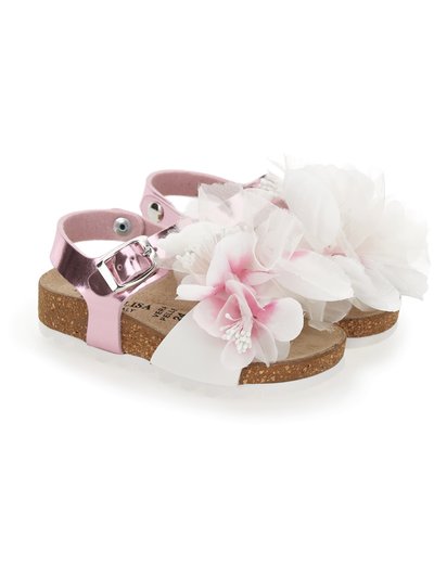 Sandalias rosas y blancas con acentos florales, suela de corcho, tiras brillantes rosas, hebilla ajustable y flores de tela blanca texturizada.