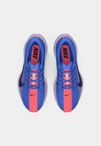 Αθλητικά παπούτσια Nike με μπλε διχτυωτό επάνω μέρος και ροζ και μοβ λεπτομέρειες, επίπεδες κορδόνες, μαλακή σόλα και ορατό λογότυπο στην γλώσσα.