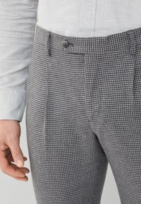 Hlače s uzorkom houndstooth u sivoj i crnoj boji s kopčanjem na dugme, s ravnim prednjim dijelom i bočnim džepovima. Teksturirana tkanina.