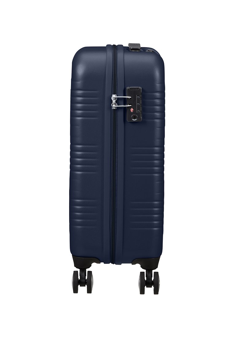 Valigia rigida blu navy con scanalature orizzontali, chiusura con cerniera, lucchetto integrato e quattro ruote nere per la mobilità.