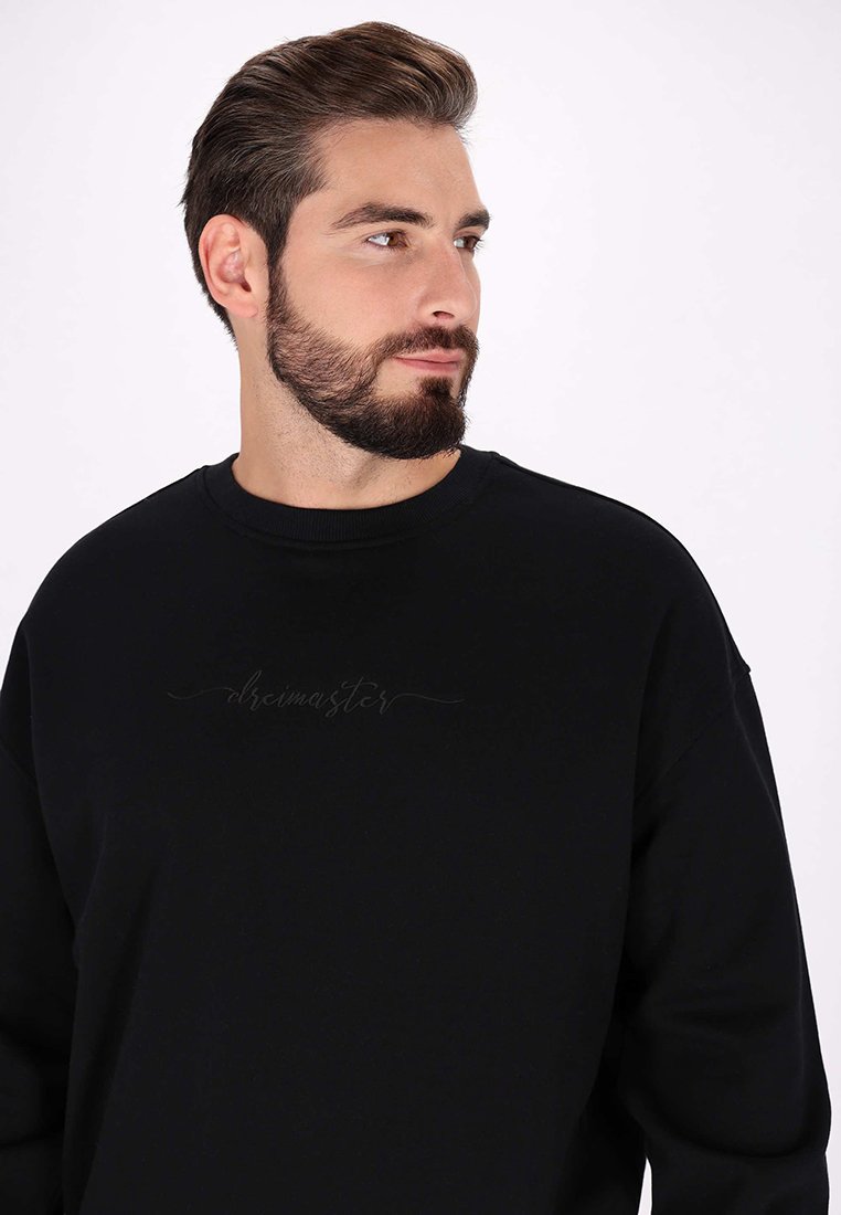 Schwarzer Pullover aus weichem Material mit Rundhalsausschnitt und einem dezenten Logo-Design in dunkler Fäden über die Brust.