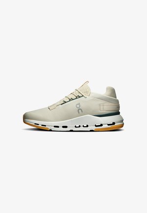 Chaussure de sport beige clair avec semelle blanche et bande de roulement orange, dotée d’une languette perforée, d’un logo latéral et d’un col de talon rembourré.
