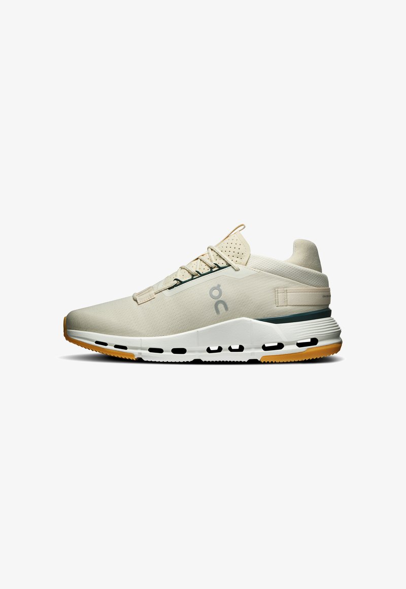 Chaussure de sport beige clair avec semelle blanche et bande de roulement orange, dotée d’une languette perforée, d’un logo latéral et d’un col de talon rembourré.