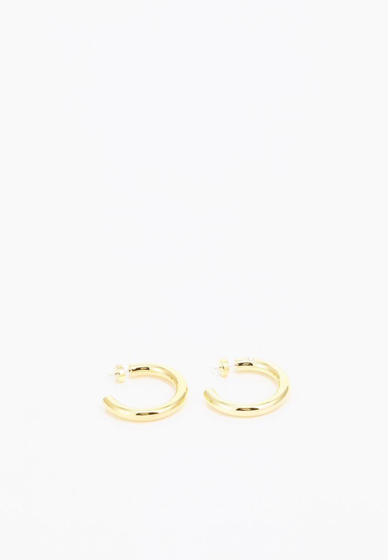 Pendientes de aro de oro con un diseño curvado y suave y un acabado pulido. Cuentan con un cierre seguro de tipo postes.