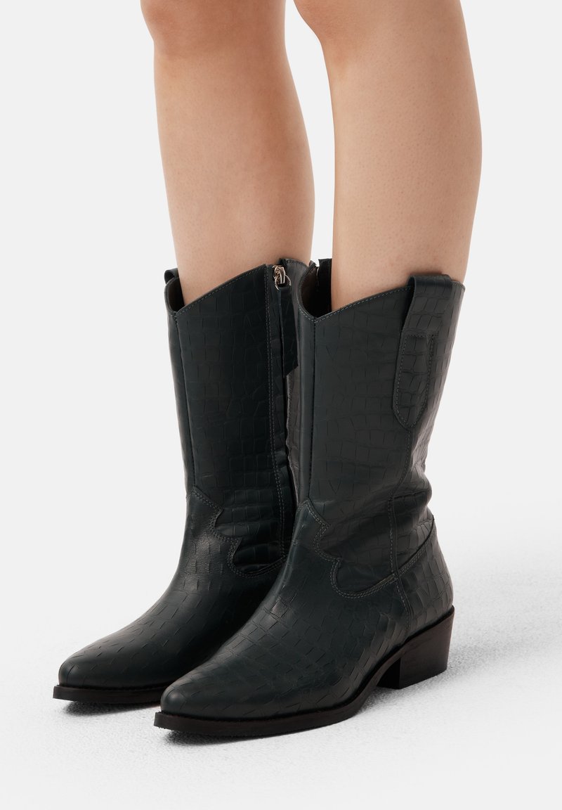 Zielone, teksturowane skórzane kowbojki, z wąskim czubkiem, niskim słupkowym obcasem i zamkiem błyskawicznym z boku, z ozdobnym przeszyciem.