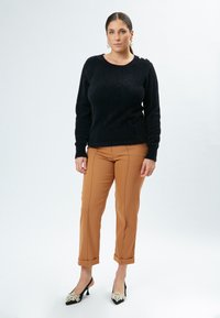 Sort fuzzy sweater med skulderknapper, tan slim bukser med side-sømme, og sorte hæle med perle detaljer.