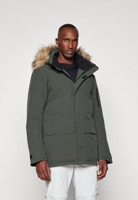 Maslinasto zeleni parka s kapuljačom obloženom krznom, zatvaranjem na patentni zatvarač i dugmadima, višestrukim džepovima i elegantnim, vremenski otpornim dizajnom.