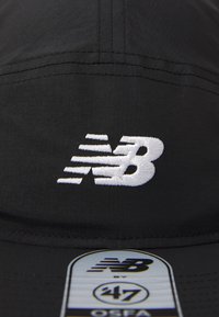 Black cap with white embroidered New Balance logo and a silver sticker labeled "NB 47 OSFA" on the brim.