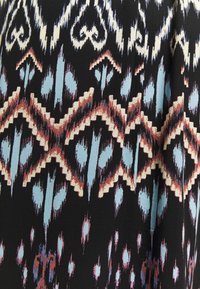 Tissu noir avec un motif géométrique Ikat en bleu clair, beige et rouille formant des losanges et des motifs abstraits.