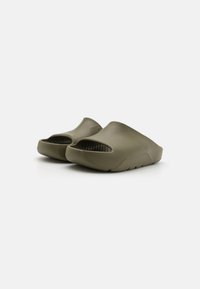Zelene klompe na slip-on od teksturirane gume, sa perforacijama za ventilaciju i debelim, oblikovanim đonom sa zakrivljenim dizajnom.