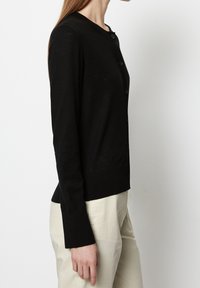 Czarny kardigan wykonany z lekkiego materiału, z okrągłym dekoltem, długimi rękawami i sześcioma guzikami z przodu.