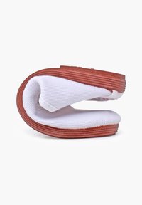Witte canvas schoen met een flexibel ontwerp, voorzien van een contrasterende bruine rubberen zool, ronde vorm en gestructureerde stof.